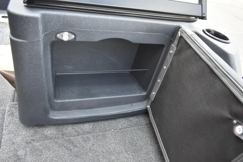 Slide: The Image of 2026 Tracker Targa V-19 WT storage compartment with open door and cup holder. - 101