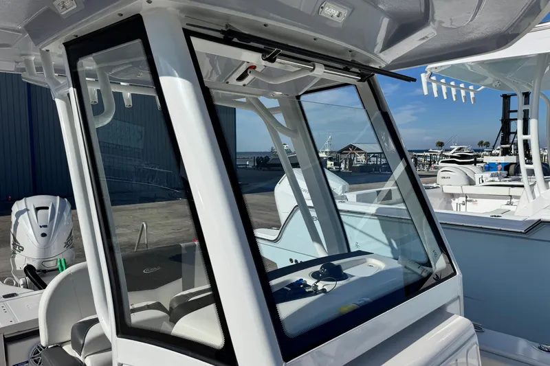 Slide: The Image of 2023 Robalo 266 Cayman boat console with clear windshield at marina. - 20