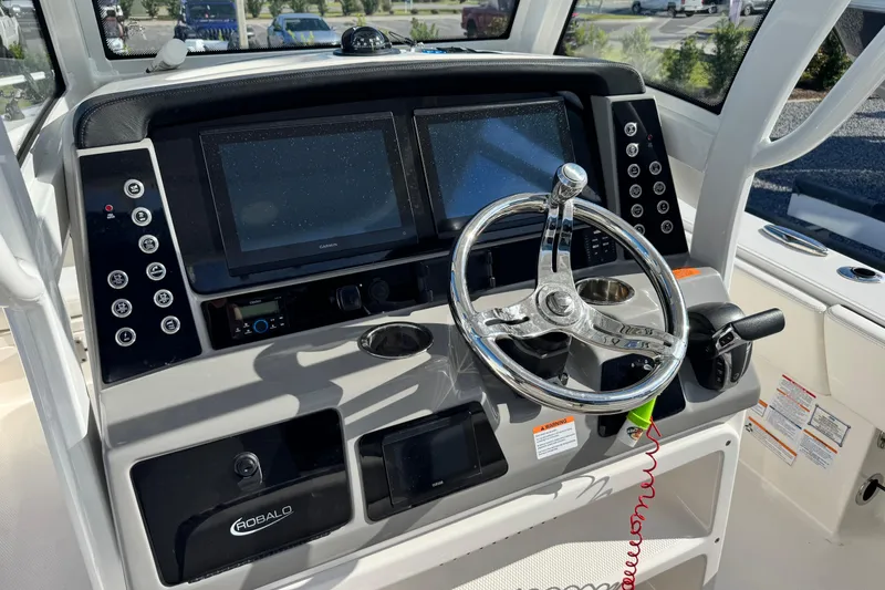 Slide: The Image of 2023 Robalo 266 Cayman boat dashboard with steering wheel and dual displays. - 22