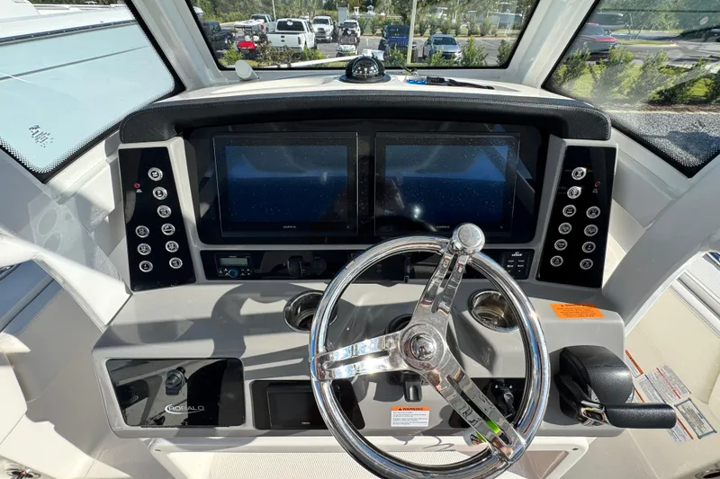 Slide: The Image of 2023 Robalo 266 Cayman boat dashboard with dual screens and steering wheel. - 23