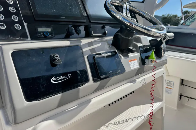 Slide: The Image of 2023 Robalo 266 Cayman boat dashboard with steering wheel and electronic controls. - 29