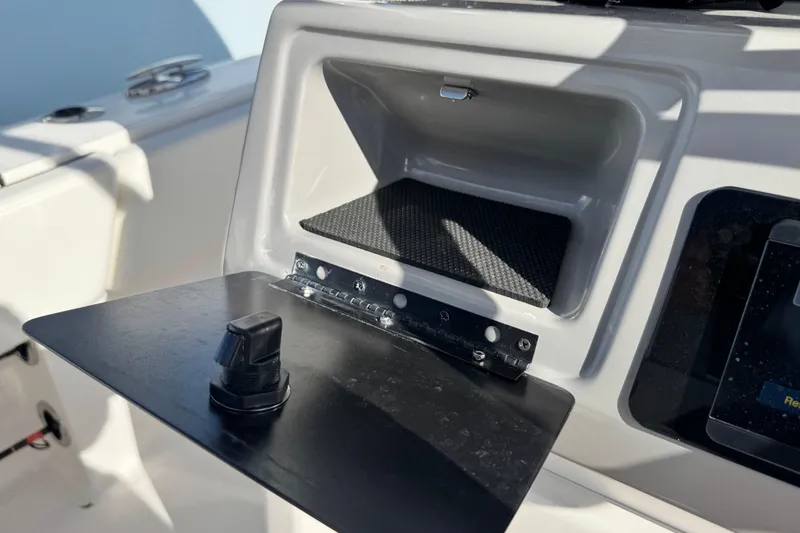 Slide: The Image of 2023 Robalo 266 Cayman boat storage compartment with open lid and control knob. - 33