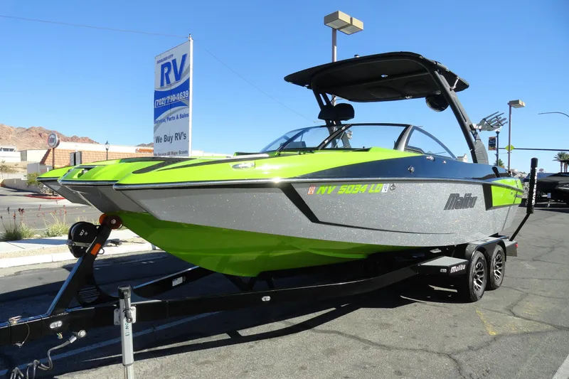 Slide: The Image of 2018 Malibu Wakesetter 24 MXZ boat on trailer, vibrant green and gray design. - 2