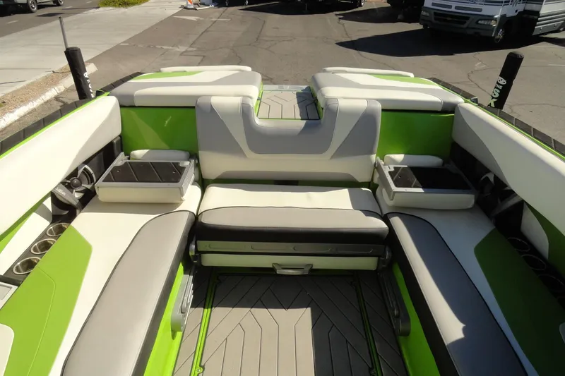 Slide: The Image of 2018 Malibu Wakesetter 24 MXZ interior with green and white seating, cup holders, and storage compartments. - 24