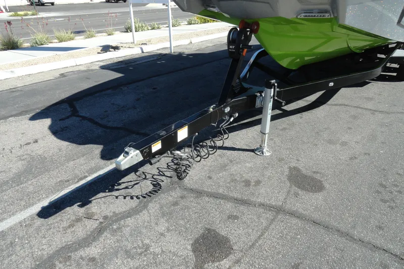 Slide: The Image of Trailer hitch of 2018 Malibu Wakesetter 24 MXZ on pavement, featuring green hull. - 29