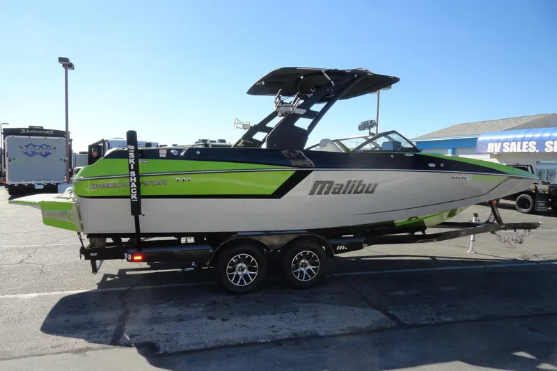 Slide: The Image of 2018 Malibu Wakesetter 24 MXZ boat on trailer, green and gray design, parked at RV sales lot. - 5