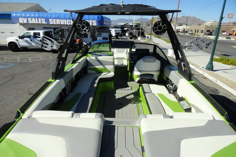 Slide: The Image of 2018 Malibu Wakesetter 24 MXZ boat interior with green and white seating, parked near RV sales. - 8