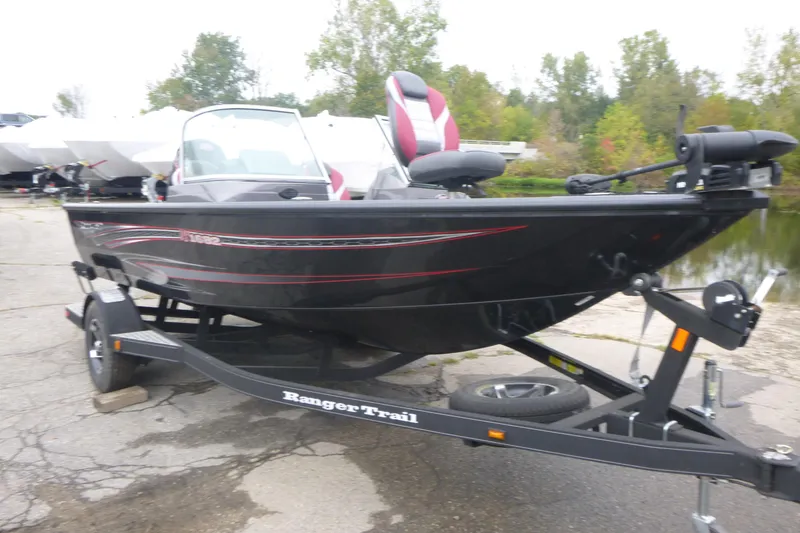 Slide: The Image of 2020 Ranger VS1682 WT boat on trailer, parked near water, with trees in background. - 3