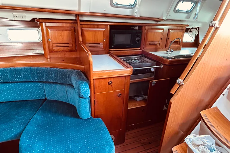 Slide: The Image of Interior of 2001 Beneteau 411 sailboat with wooden cabinetry and blue seating. - 10