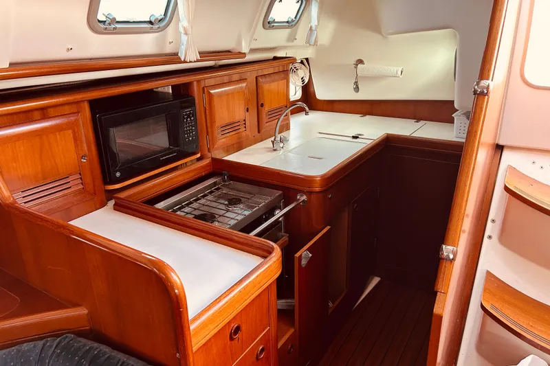 Slide: The Image of 2001 Beneteau 411 yacht kitchen with wood cabinetry, stove, microwave, and sink. - 11
