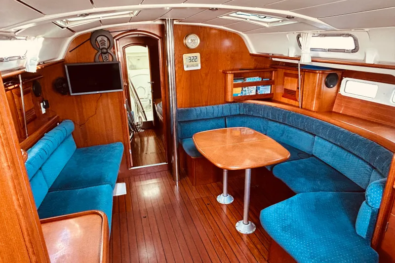 Slide: The Image of Interior of 2001 Beneteau 411 sailboat with blue seating and wooden finishes. - 2