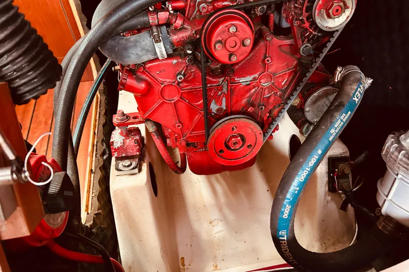 Slide: The Image of Engine compartment of a 2001 Beneteau 411 sailboat, featuring a red motor and hoses. - 24