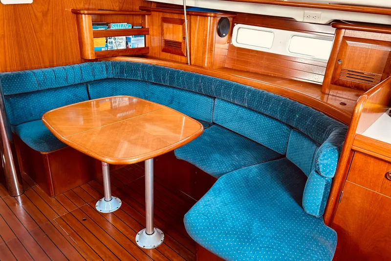 Slide: The Image of Interior of 2001 Beneteau 411 sailboat with blue cushioned seating and wooden table. - 3