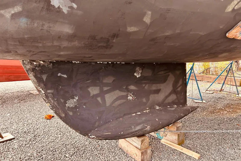 Slide: The Image of 2001 Beneteau 411 sailboat keel on dry dock, showing wear and maintenance needs. - 35