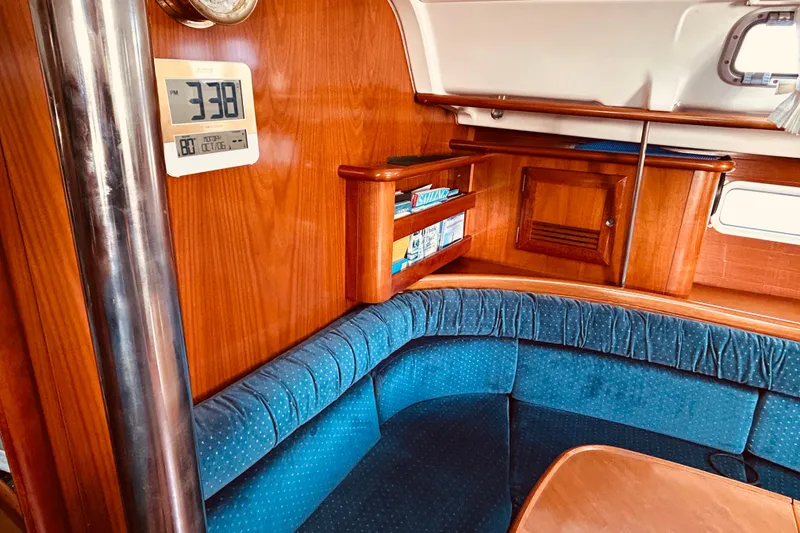 Slide: The Image of Interior of 2001 Beneteau 411 sailboat with blue seating and wooden cabinetry. - 9