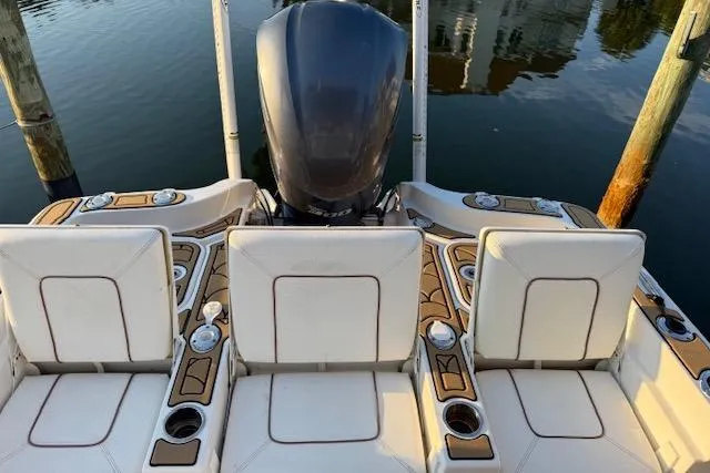 Slide: The Image of 2018 Sea Hunt BX 25 FS boat interior with seating and motor, docked on calm water. - 4