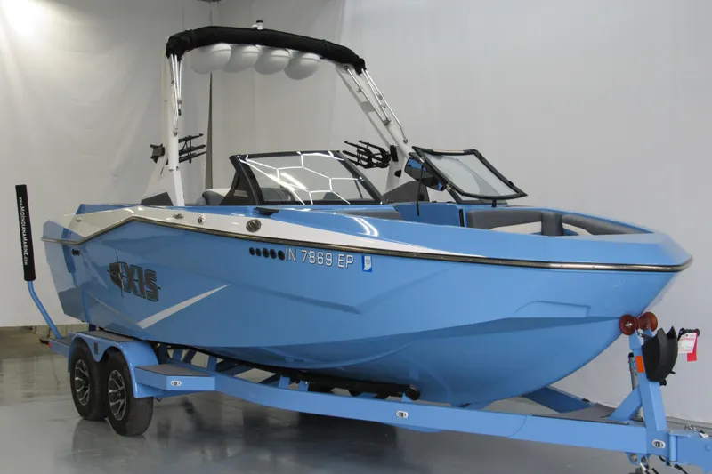 Slide: The Image of 2024 Axis T220 boat in blue on a trailer, displayed indoors. - 1