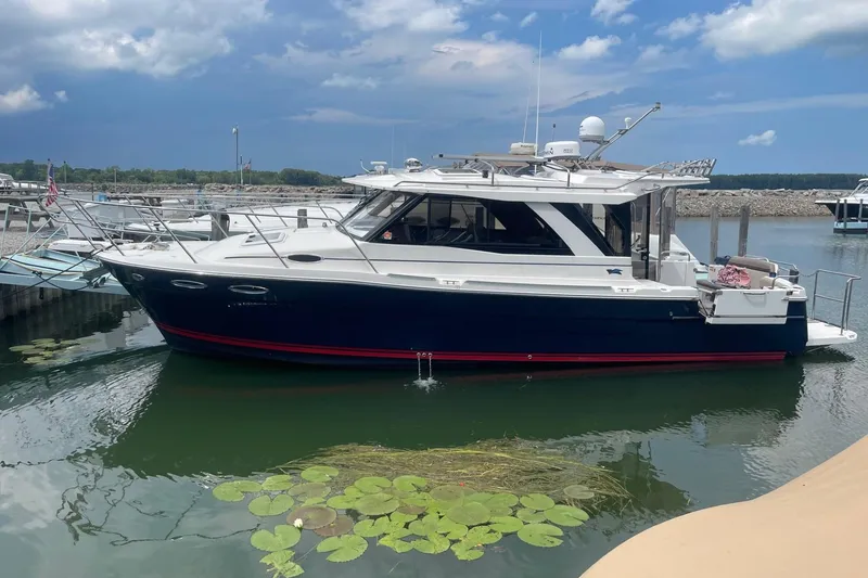 Slide: The Image of 2022 Cutwater C-30 Sedan boat docked on calm water with lily pads nearby. - 0