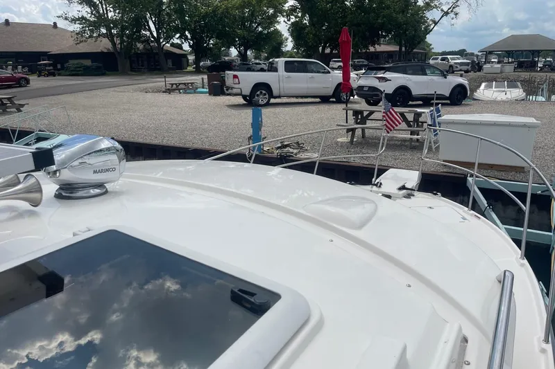 Slide: The Image of 2022 Cutwater C-30 Sedan docked, with cars and picnic area in the background. - 3