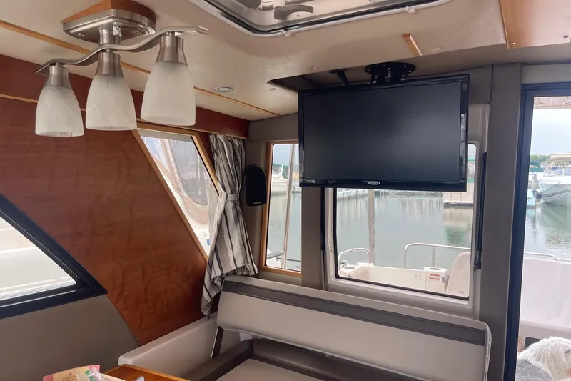 Slide: The Image of Interior of 2022 Cutwater C-30 Sedan with TV, seating, and window view of marina. - 6