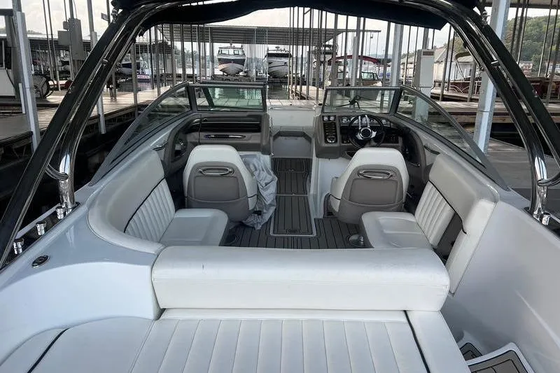 Slide: The Image of 2006 Cobalt 272 boat interior with white seating and modern dashboard at a marina. - 3