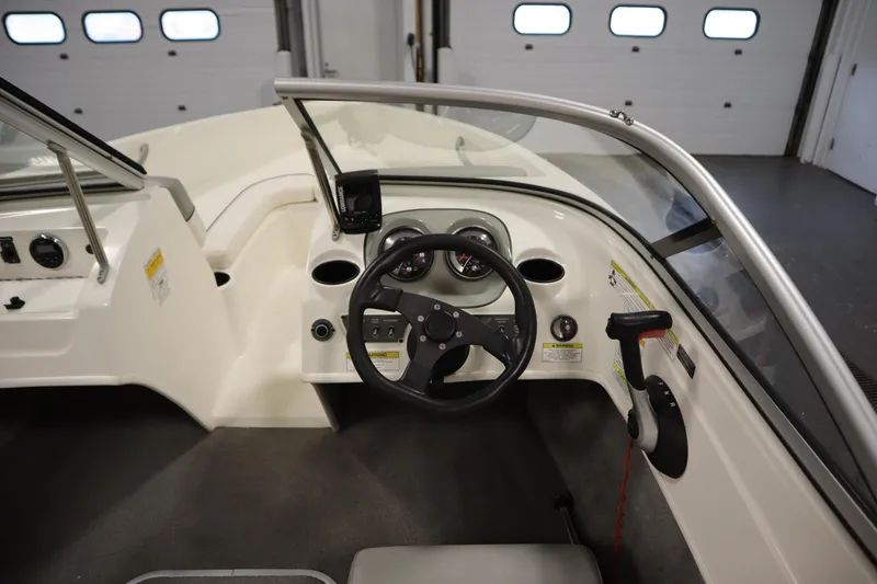 Slide: The Image of 2013 Bayliner 175 Bowrider dashboard with steering wheel and control panel in a garage setting. - 15