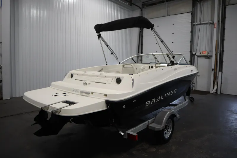 Slide: The Image of 2013 Bayliner 175 Bowrider boat in a garage, featuring a sleek design and black hull. - 5