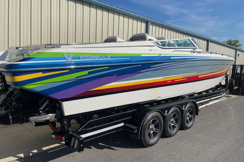 Slide: The Image of 2004 Formula 382 FASTech speedboat with vibrant stripes on a triple-axle trailer. - 2
