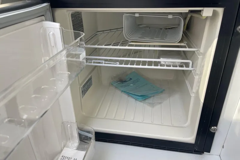 Slide: The Image of Empty refrigerator interior with shelves, documents, and a small container inside a 2004 Formula 382 FASTech. - 44
