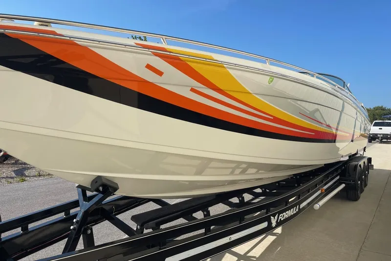 Slide: The Image of 2004 Formula 382 FASTech boat with vibrant orange and yellow graphics on a trailer. - 5