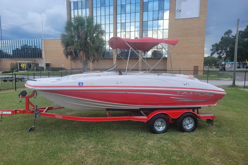 The Image of 2008 Tahoe 195 I/O boat with red trailer, parked on grass near a building. - 0