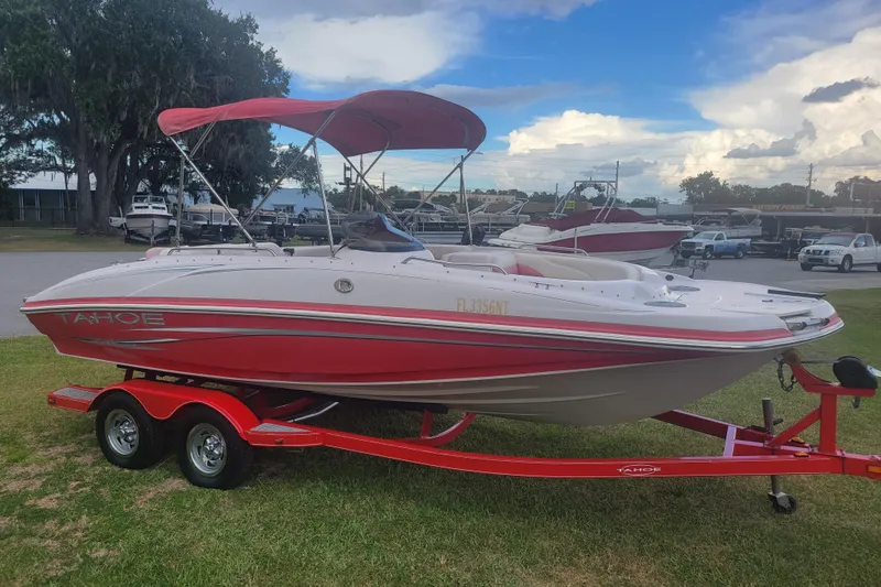 Slide: The Image of 2008 Tahoe 195 I/O boat with red accents on a matching trailer, parked outdoors. - 2