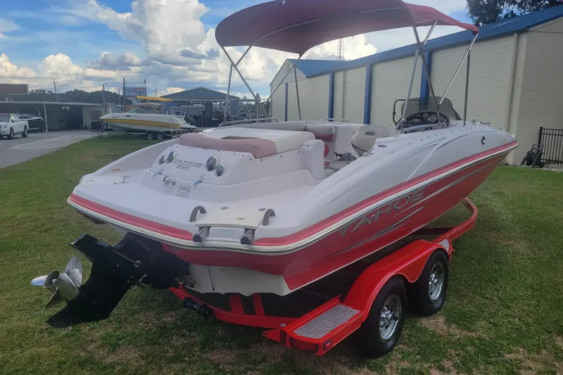 Slide: The Image of 2008 Tahoe 195 I/O boat with red trailer, parked on grass under a cloudy sky. - 3