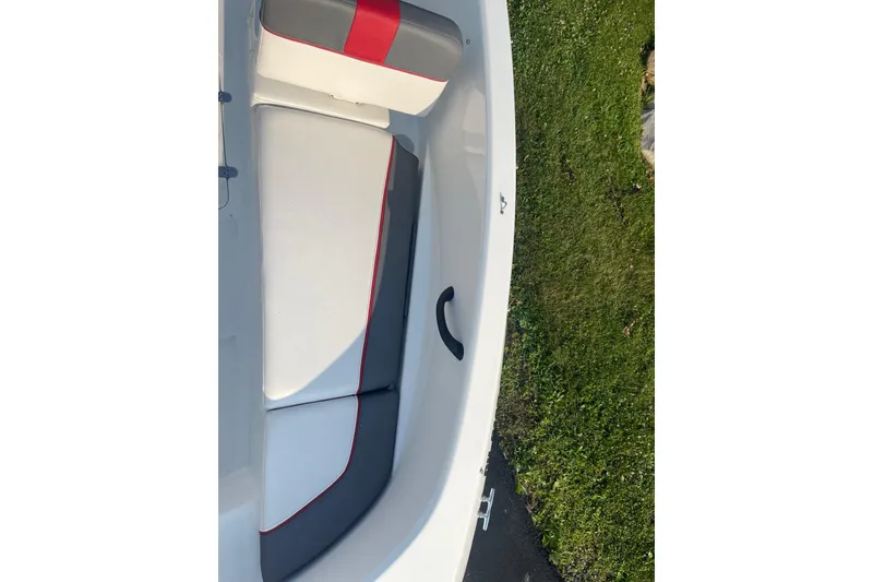 Slide: The Image of 2021 Tahoe T-16 boat interior with red and gray seating, grassy background. - 17