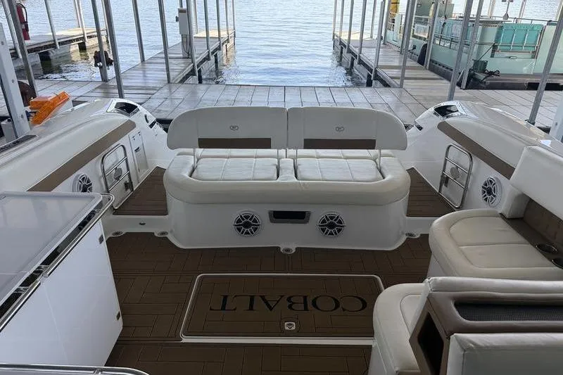 Slide: The Image of 2015 Cobalt A40 boat interior with white seating and wood flooring at a dock. - 15