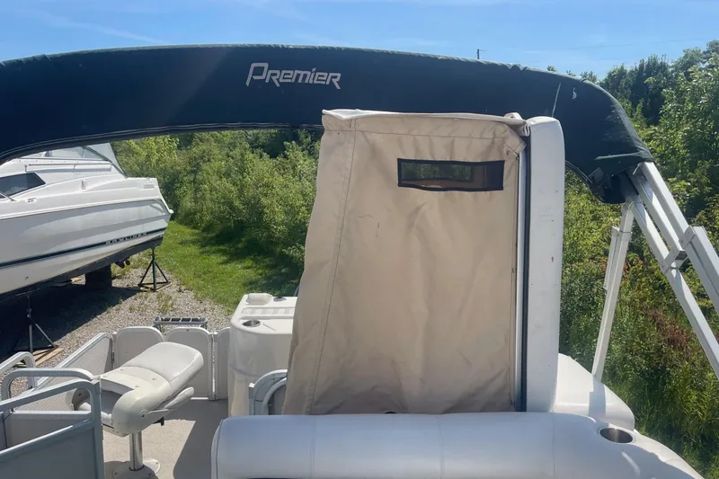 Slide: The Image of 2007 Premier 231 Alante boat interior with seating and storage, surrounded by greenery. - 18