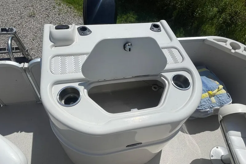 Slide: The Image of 2007 Premier 231 Alante pontoon boat interior with seating and console, parked on gravel. - 20