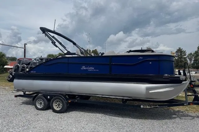 Slide: The Image of 2026 Barletta ARIA 22UC pontoon boat on trailer, parked outdoors under cloudy sky. - 1