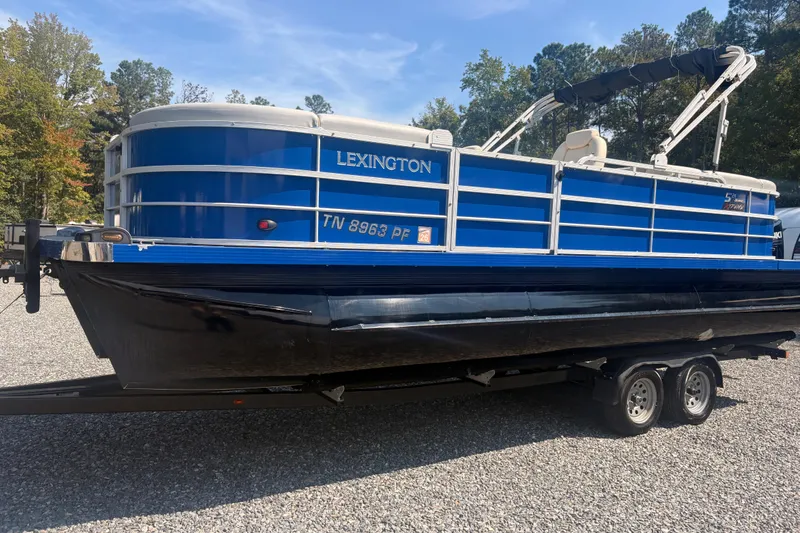 The Image of 2022 Lexington 524 pontoon boat on trailer, blue and white design, parked outdoors. - 1