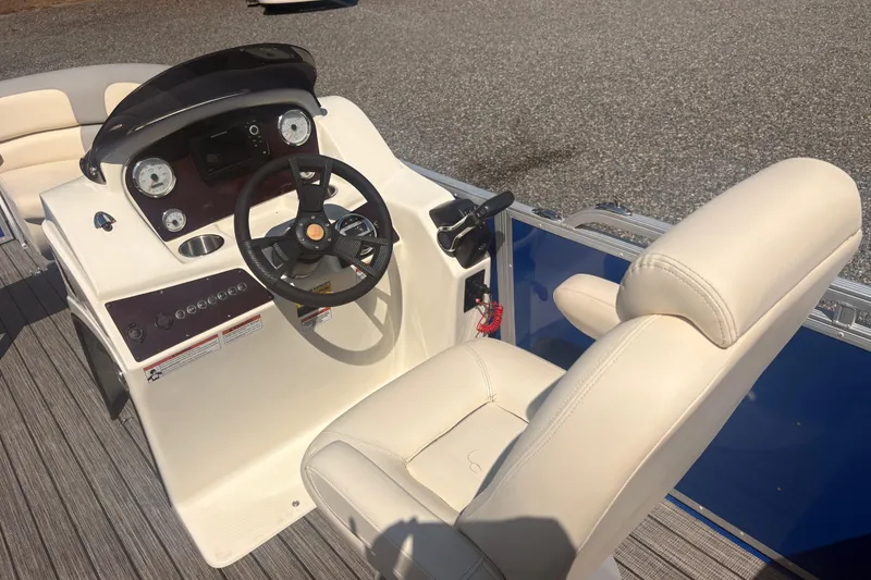 Slide: The Image of 2022 Lexington 524 boat cockpit with steering wheel and beige seating. - 10
