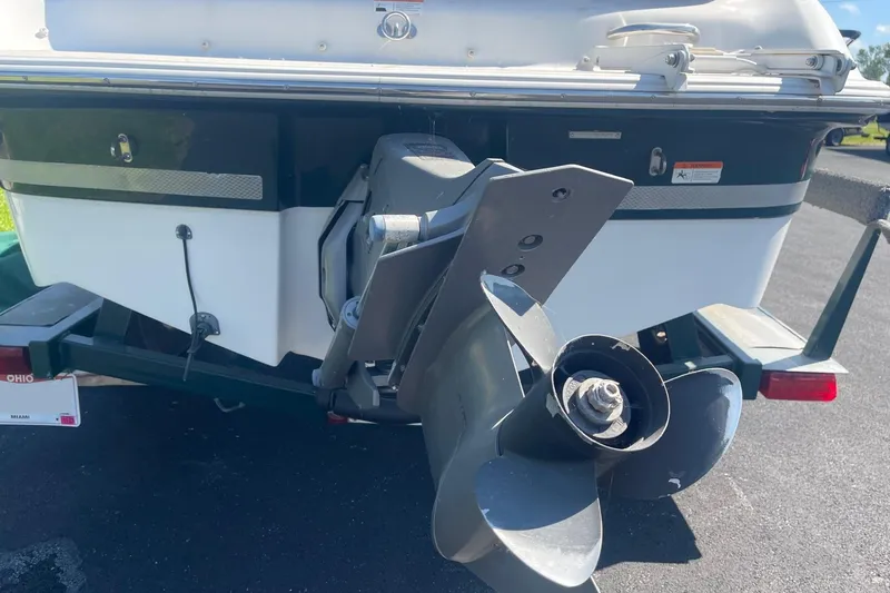 Slide: The Image of 2003 Four Winns 180 Horizon boat stern with propeller, parked on asphalt. - 2