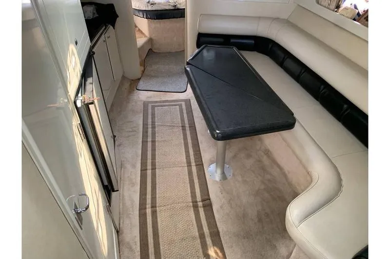 Slide: The Image of 1999 Wellcraft 45 Excalibur interior with beige seating, black table, and kitchenette. - 11