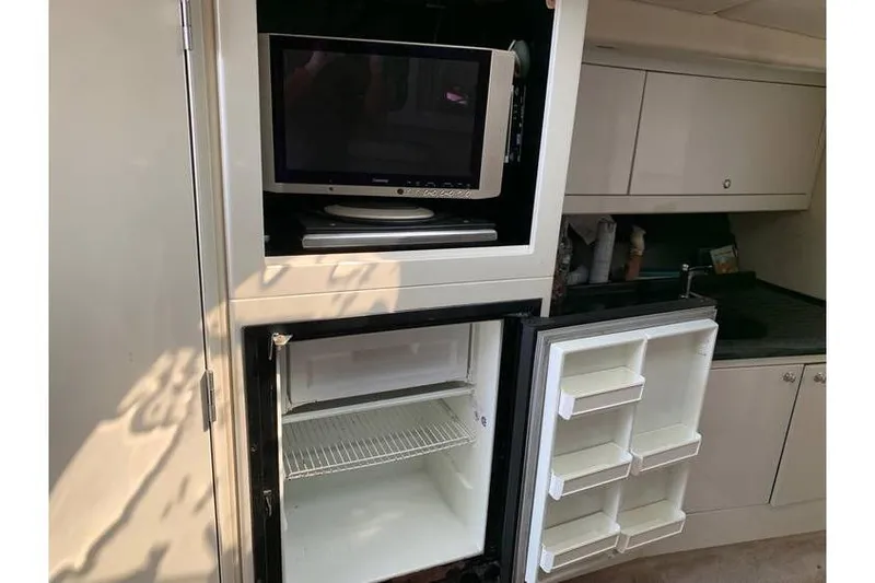 Slide: The Image of 1999 Wellcraft 45 Excalibur interior with TV and open refrigerator in kitchenette. - 6