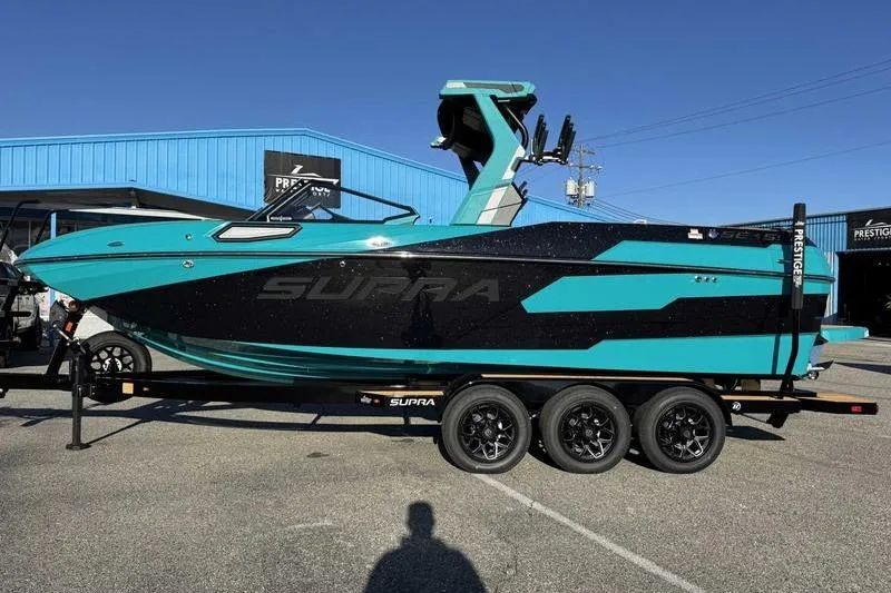 The Image of 2026 Supra SE boat in teal and black on a trailer, parked outdoors. - 1