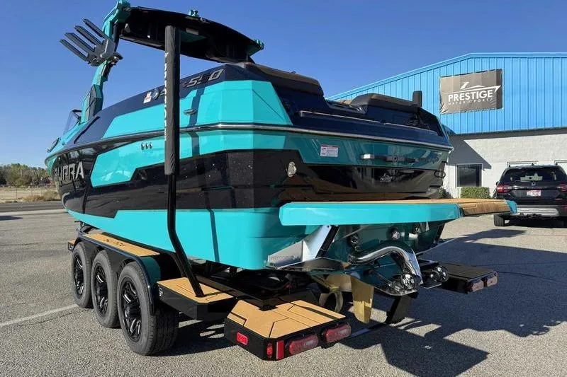 Slide: The Image of 2026 Supra SE boat on trailer, vibrant teal and black design, parked outside Prestige building. - 11