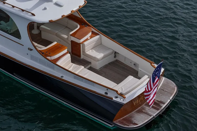 Slide: The Image of 2015 Hinckley Picnic Boat 37 MKIII with elegant seating and American flag on water. - 17