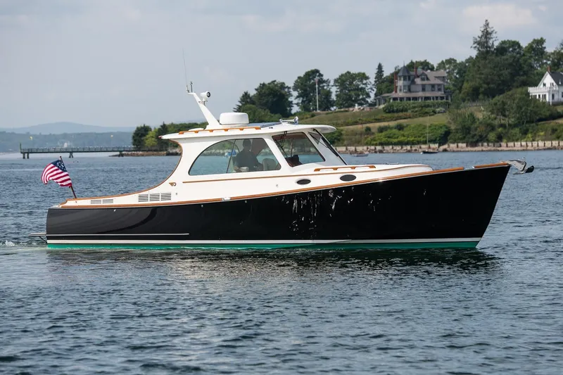 Slide: The Image of 2015 Hinckley Picnic Boat 37 MKIII cruising on a scenic waterway with American flag. - 2