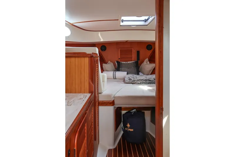 Slide: The Image of 2015 Hinckley Picnic Boat 37 MKIII cabin interior with cozy bedding and wooden finishes. - 45