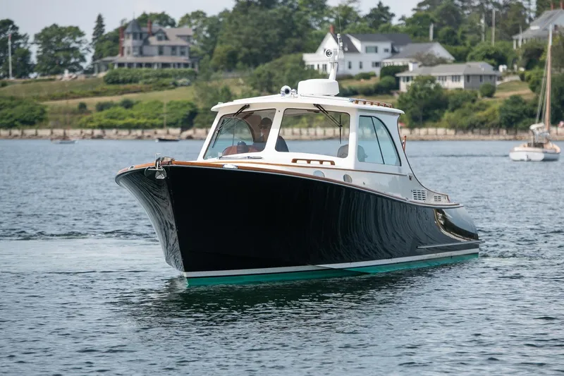 Slide: The Image of 2015 Hinckley Picnic Boat 37 MKIII cruising on calm waters near shoreline homes. - 5