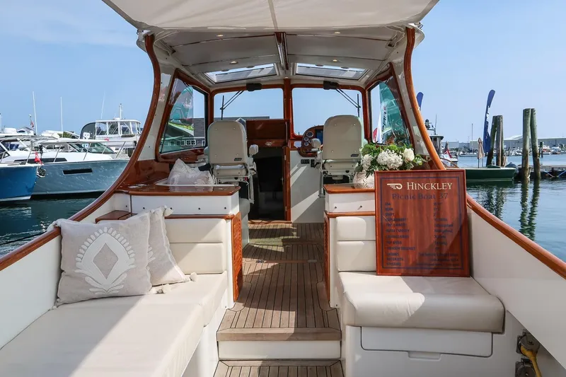 Slide: The Image of 2015 Hinckley Picnic Boat 37 MKIII interior with elegant seating and wooden accents at a marina. - 29